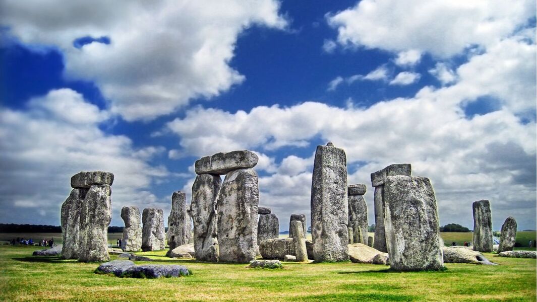 "Stonehenge stone circle in Wiltshire with large standing stones under a blue sky with clouds"